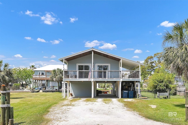 310 W 3rd Ave, Gulf Shores, AL 36542 - view of front facade with driveway, fence, a carport, and a front lawn