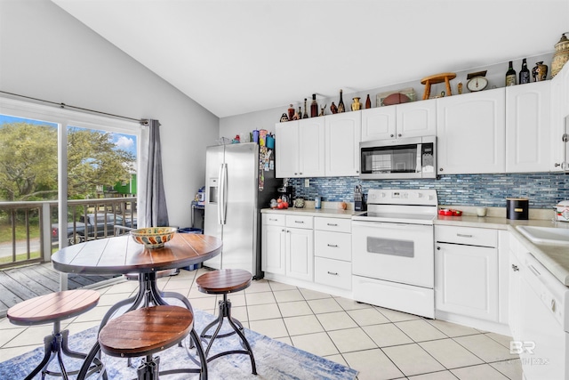 310 W 3rd Ave, Gulf Shores, AL 36542 - kitchen featuring appliances with stainless steel finishes, tasteful backsplash, light countertops, and vaulted ceiling