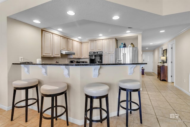 527 E Beach Blvd Unit 802, Gulf Shores, AL 36542 - kitchen featuring freestanding refrigerator, oven, under cabinet range hood, a breakfast bar area, and light tile patterned flooring