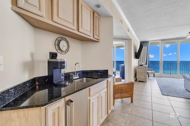527 E Beach Blvd Unit 802, Gulf Shores, AL 36542 - kitchen featuring light brown cabinetry, light tile patterned flooring, open floor plan, dark stone counters, and a textured ceiling