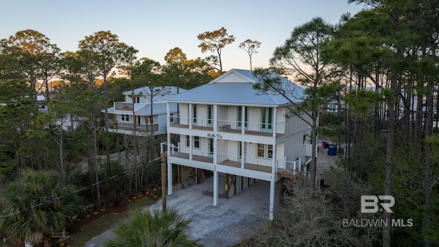 1438 Bienville Blvd Unit B, Dauphin Island, AL 36528 - back of house at dusk featuring a balcony, a carport, and metal roof
