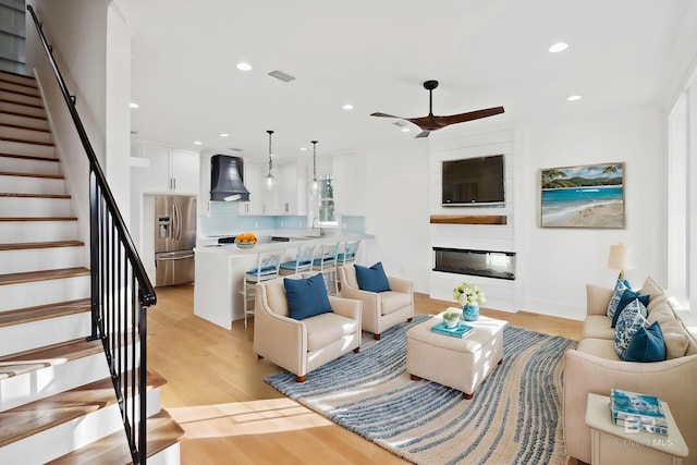 1438 Bienville Blvd Unit B, Dauphin Island, AL 36528 - living room featuring light wood-type flooring, stairway, recessed lighting, ceiling fan, and a large fireplace