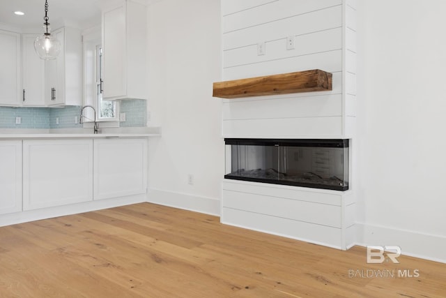 1438 Bienville Blvd Unit B, Dauphin Island, AL 36528 - kitchen with baseboards, white cabinetry, light wood-style floors, decorative backsplash, and decorative light fixtures