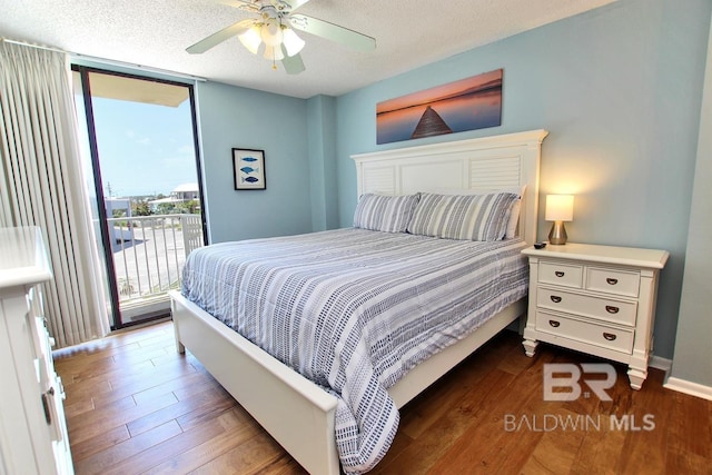 bedroom featuring a wall of windows, wood-type flooring, access to exterior, ceiling fan, and a textured ceiling