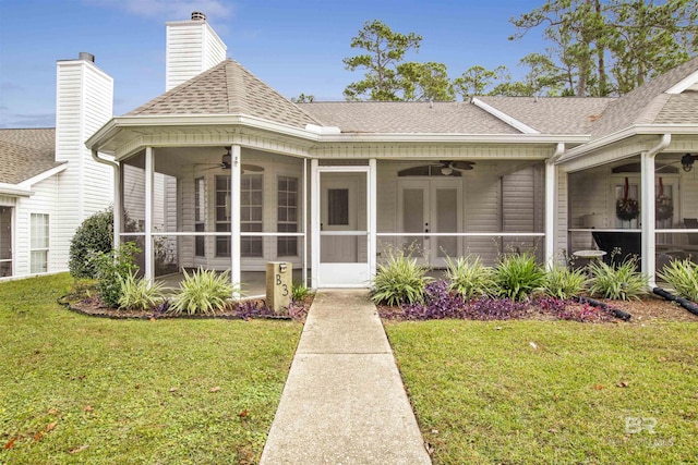 view of exterior entry with a yard and ceiling fan