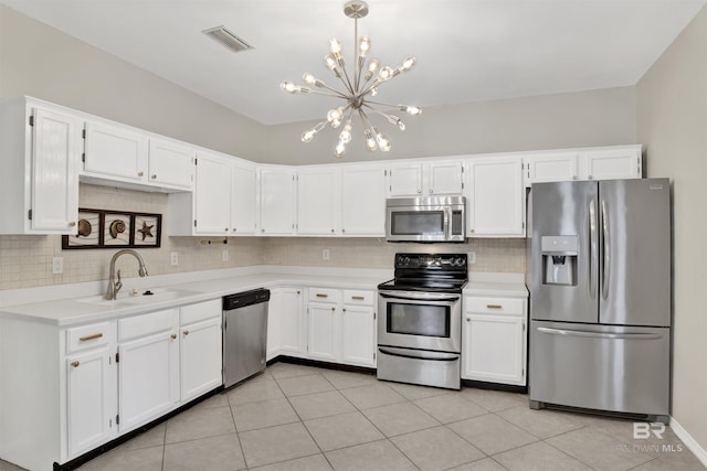 kitchen featuring appliances with stainless steel finishes, white cabinetry, an inviting chandelier, and sink