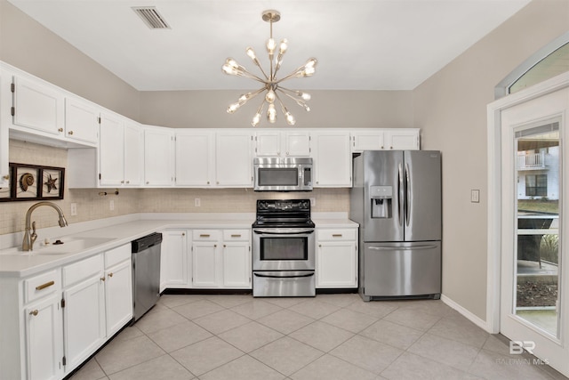 kitchen featuring appliances with stainless steel finishes, white cabinets, sink, a chandelier, and hanging light fixtures