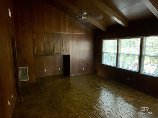 spare room with vaulted ceiling with beams, ceiling fan, and wooden walls