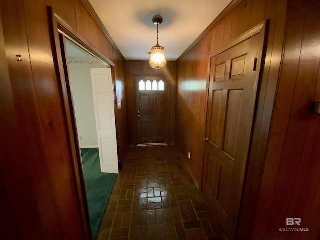 doorway featuring wood walls and crown molding