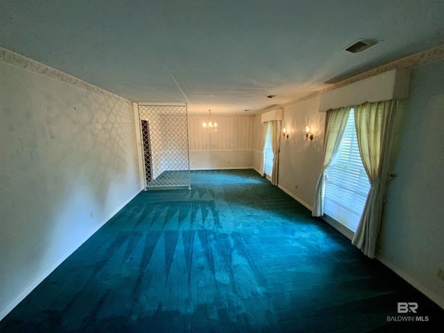 spare room with a chandelier and dark carpet