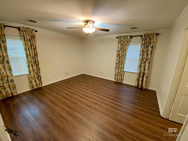 empty room featuring ceiling fan, crown molding, and dark wood-type flooring