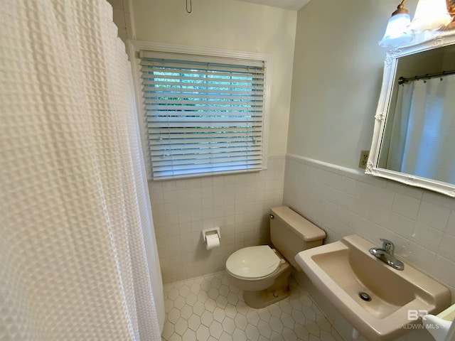 bathroom featuring tile patterned floors, sink, tile walls, and toilet