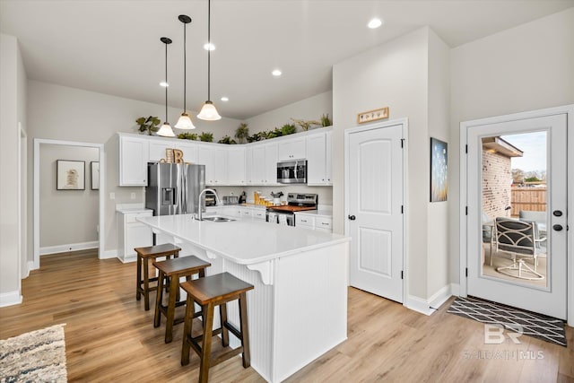 kitchen featuring sink, decorative light fixtures, white cabinetry, a center island with sink, and appliances with stainless steel finishes