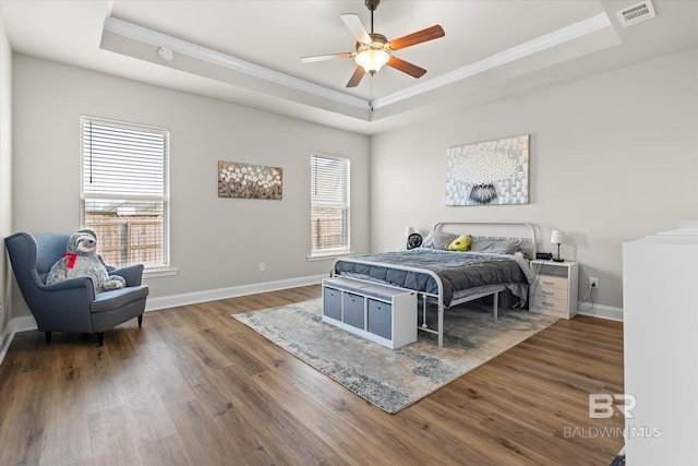 bedroom with ceiling fan, multiple windows, and a raised ceiling