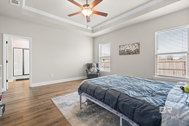 bedroom featuring ceiling fan, a tray ceiling, crown molding, and hardwood / wood-style floors