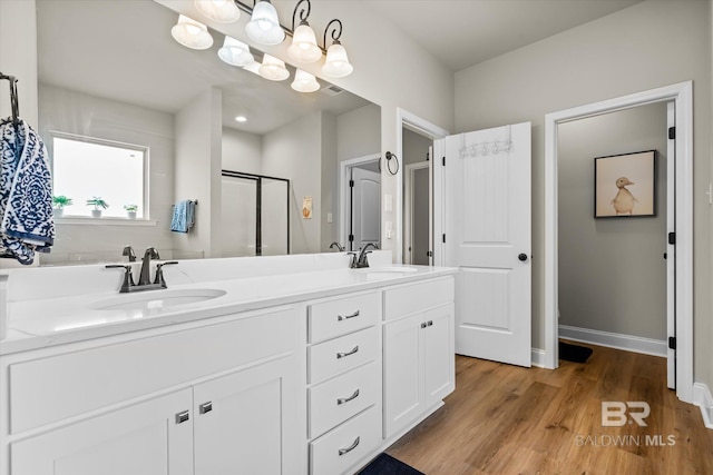 bathroom with a shower with shower door, vanity, and wood-type flooring