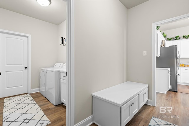 laundry area with hardwood / wood-style flooring, washing machine and dryer, and cabinets