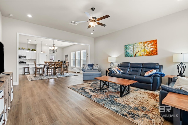 living room featuring light wood-type flooring and ceiling fan with notable chandelier