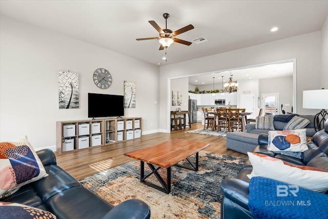 living room featuring ceiling fan with notable chandelier and wood-type flooring