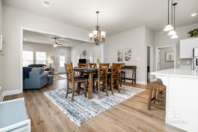 dining room with ceiling fan with notable chandelier and light wood-type flooring