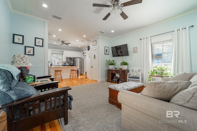 living room featuring ceiling fan, crown molding, and light hardwood / wood-style flooring