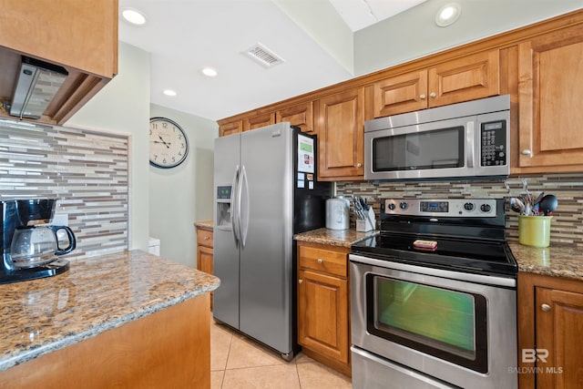 23044 Perdido Beach Blvd Unit 141, Orange Beach, AL 36561 - kitchen with appliances with stainless steel finishes, decorative backsplash, brown cabinetry, light stone counters, and recessed lighting