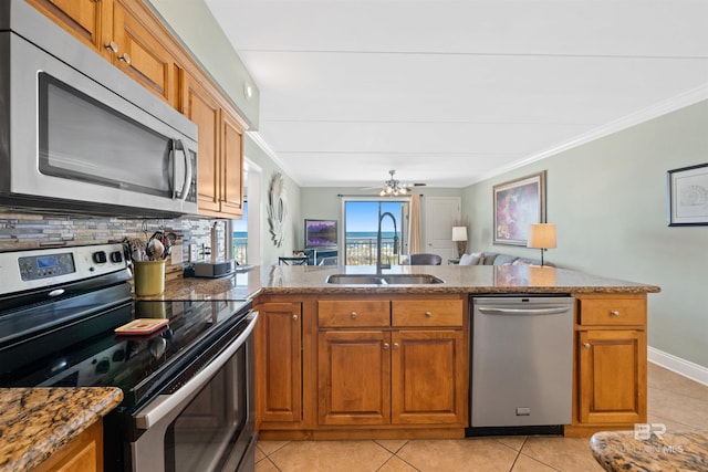 23044 Perdido Beach Blvd Unit 141, Orange Beach, AL 36561 - kitchen with appliances with stainless steel finishes, a sink, brown cabinets, crown molding, and light tile patterned floors