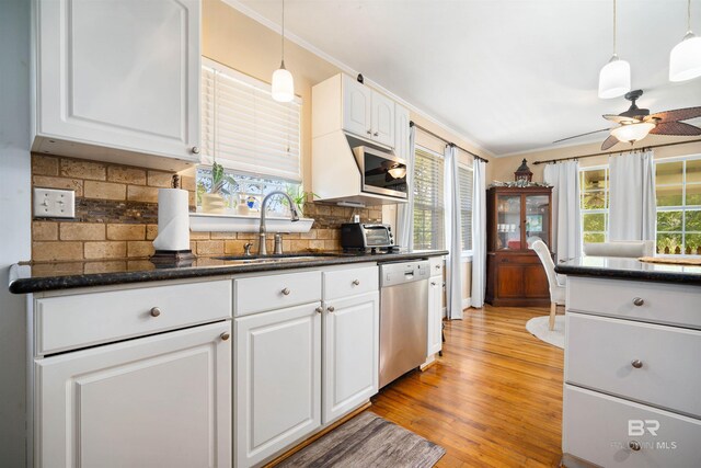 kitchen with appliances with stainless steel finishes, light hardwood / wood-style floors, white cabinets, backsplash, and sink