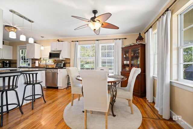 dining room featuring light hardwood / wood-style flooring, ceiling fan, ornamental molding, and sink