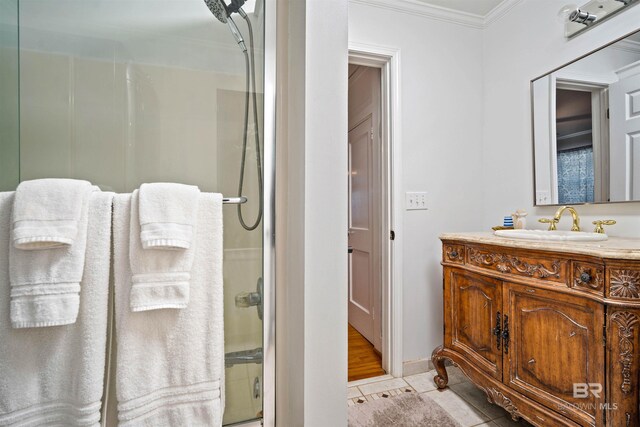 bathroom with vanity, a shower with shower door, tile patterned flooring, and crown molding