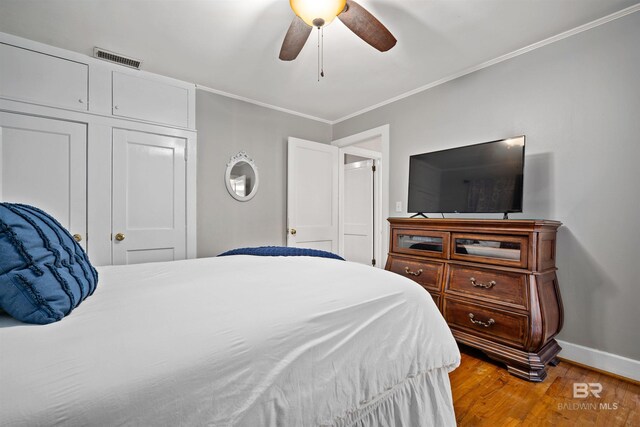 bedroom featuring a closet, light hardwood / wood-style floors, ceiling fan, and crown molding