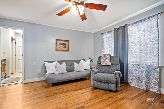 living room with wood-type flooring, ornamental molding, and ceiling fan