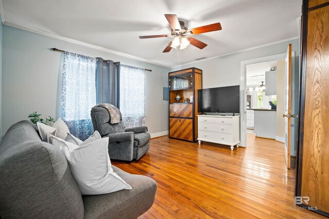 living room featuring ornamental molding, light wood-type flooring, and ceiling fan