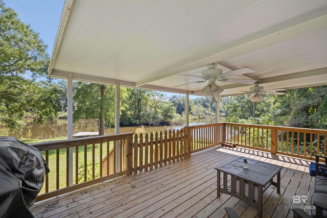 deck with a lawn, a water view, ceiling fan, and a grill