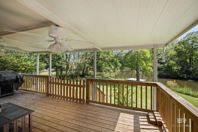 wooden deck with ceiling fan, area for grilling, a yard, and a water view