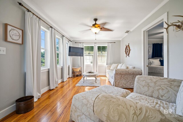 living room with ornamental molding, light wood-type flooring, and ceiling fan