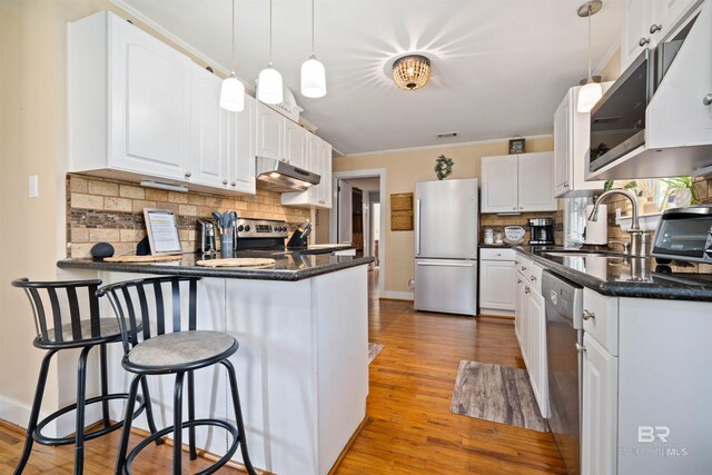 kitchen featuring light hardwood / wood-style flooring, stainless steel appliances, white cabinets, and backsplash