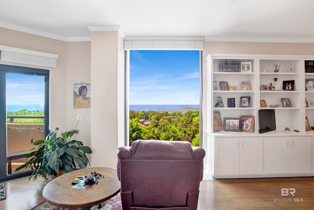 living room featuring a water view, hardwood / wood-style flooring, and crown molding