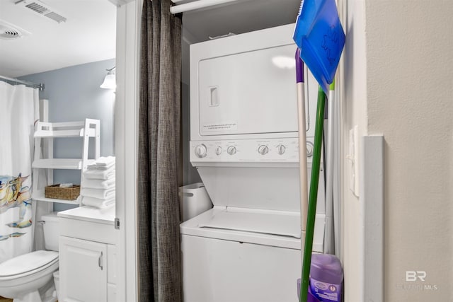 laundry area featuring stacked washing maching and dryer and visible vents