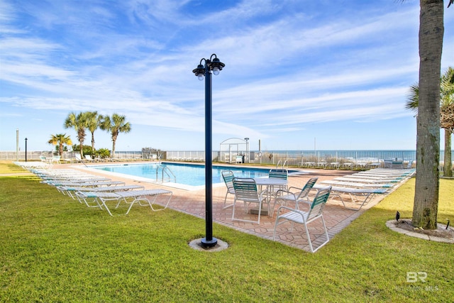 community pool with fence, a lawn, and a patio