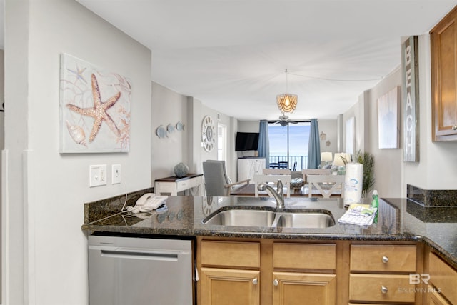 kitchen featuring pendant lighting, stainless steel dishwasher, open floor plan, a sink, and dark stone counters