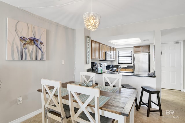 dining area featuring a notable chandelier, baseboards, and light tile patterned floors