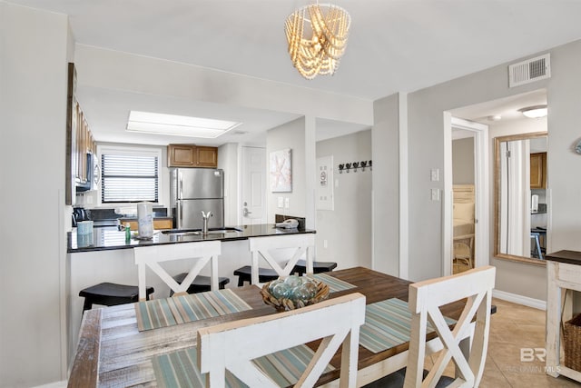 dining space with light tile patterned floors, a chandelier, visible vents, and baseboards