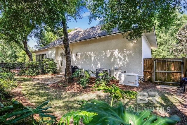 rear view of property featuring brick siding, fence, and a gate