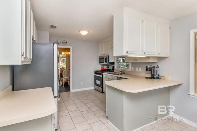 kitchen featuring sink, kitchen peninsula, white cabinetry, appliances with stainless steel finishes, and a breakfast bar area