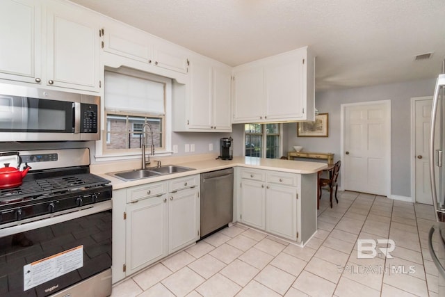 kitchen featuring appliances with stainless steel finishes, kitchen peninsula, white cabinetry, and sink