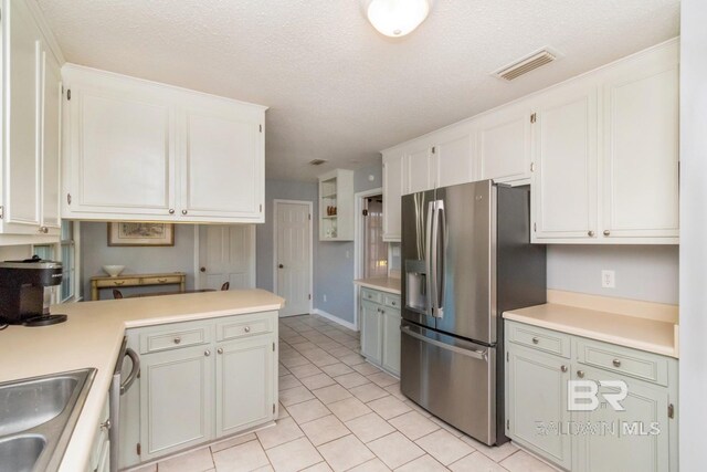 kitchen featuring a textured ceiling, stainless steel appliances, and white cabinetry