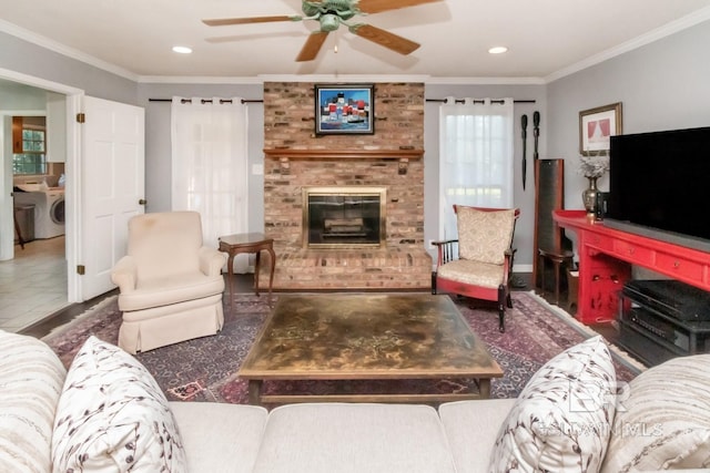 living room with a fireplace, ceiling fan, washing machine and clothes dryer, and crown molding