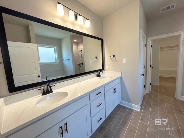 full bathroom with visible vents, a stall shower, baseboards, and a sink