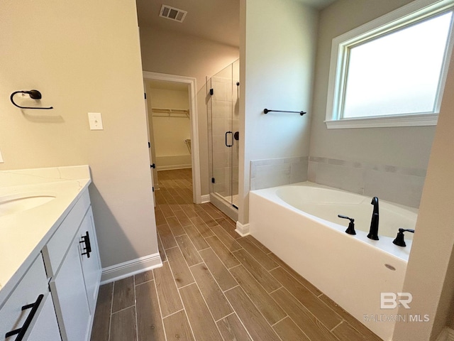 full bathroom featuring visible vents, wood finish floors, a stall shower, a spacious closet, and a bath